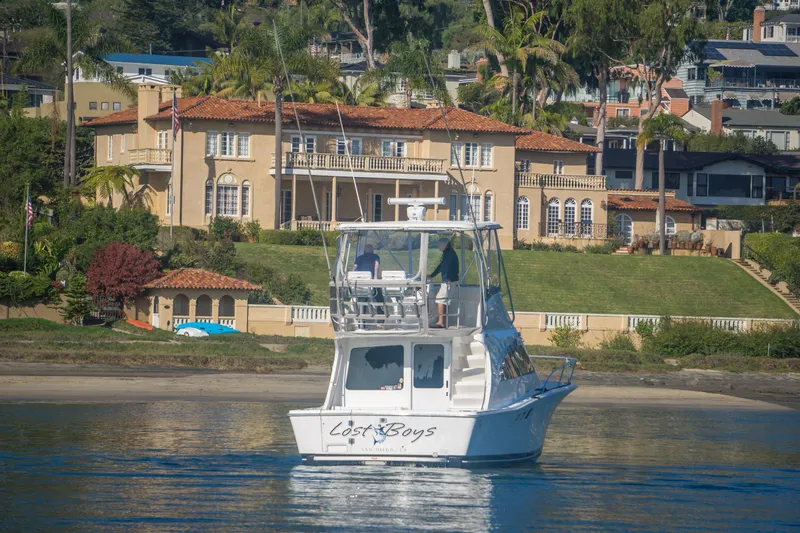 Lost Boys Yacht Photos Pics 2002 Luhrs 36 Convertible yacht on water near luxurious waterfront mansion.