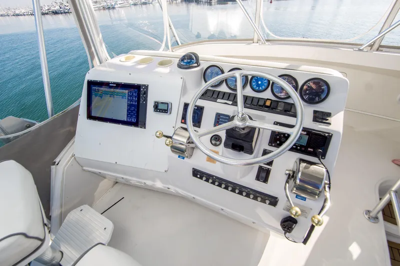 Lost Boys Yacht Photos Pics 2002 Luhrs 36 Convertible helm with navigation equipment and steering wheel, overlooking marina.