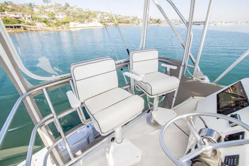 Lost Boys Yacht Photos Pics 2002 Luhrs 36 Convertible boat helm with two white captain chairs overlooking serene water.