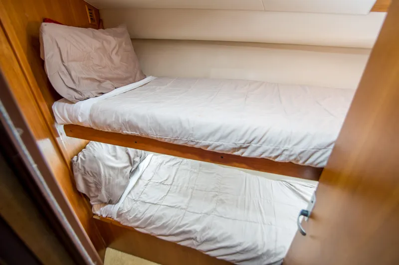 Lost Boys Yacht Photos Pics Bunk beds in 2002 Luhrs 36 Convertible yacht cabin, featuring wooden interior and white bedding.