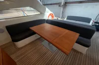 Luxurious seating area on 2007 Astondoa 53 Open yacht with wooden table and cushioned benches.