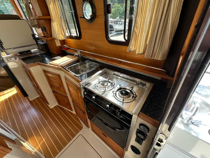 Yacht Photos Pics 2014 Ranger Tugs R-31S interior kitchen with stove, sink, and wooden cabinetry.