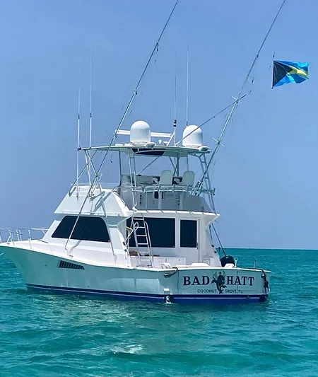 Bad Hatt Yacht Photos Pics 1999 Viking Conv Sport Fisher boat on turquoise water, flying a flag.