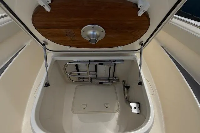  Yacht Photos Pics 2026 Scout 288 LXF boat storage compartment with wooden lid and metal ladder.