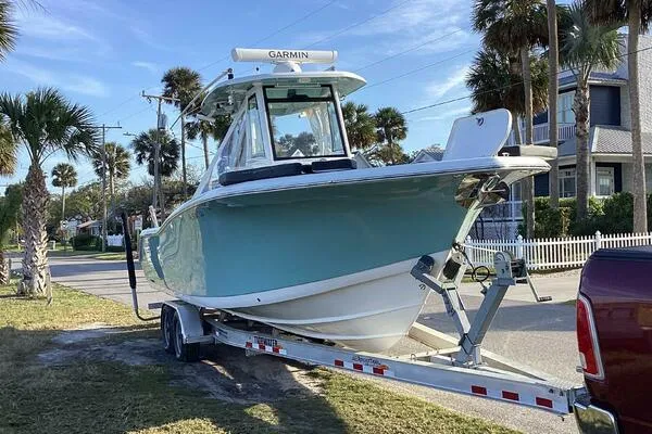  Yacht Photos Pics 2021 Tidewater 280 CC Adventure boat on trailer, parked near palm trees and houses.