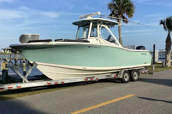  Yacht Photos Pics 2021 Tidewater 280 CC Adventure boat on trailer near palm trees and waterfront.