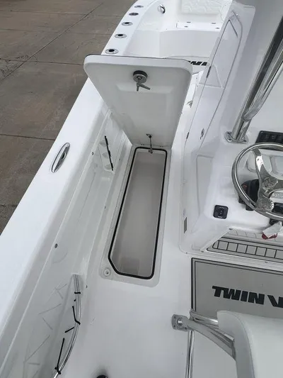  Yacht Photos Pics 2024 Twin Vee 280 STX boat interior with open storage compartment and steering wheel.