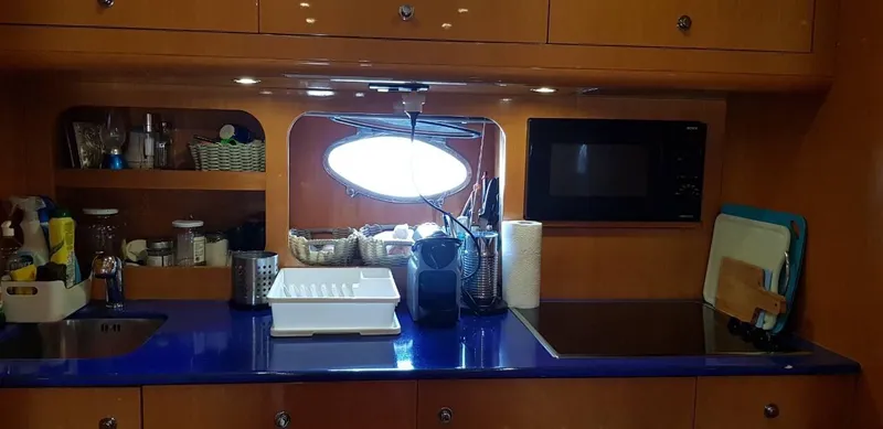  Yacht Photos Pics Kitchen area of a 2004 Uniesse 57 yacht with blue countertop and modern appliances.