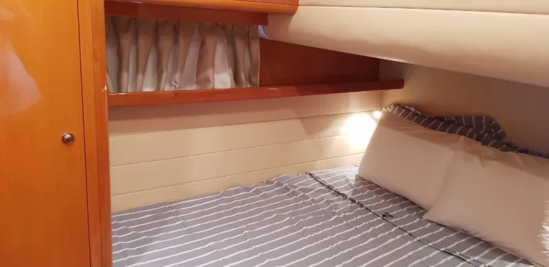  Yacht Photos Pics Cozy cabin interior of 2004 Uniesse 57 yacht with striped bedding and wooden accents.