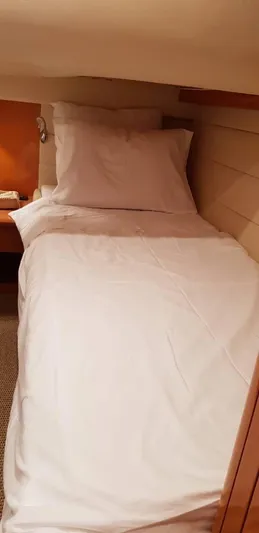  Yacht Photos Pics Cozy cabin bed in a 2004 Uniesse 57 yacht, featuring white linens and wooden accents.