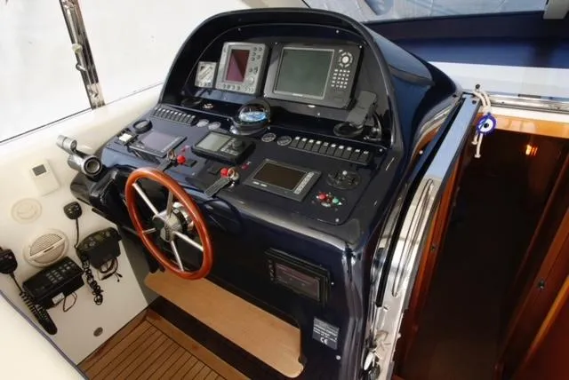  Yacht Photos Pics Control panel of a 2004 Uniesse 57 yacht with navigation equipment and wooden steering wheel.