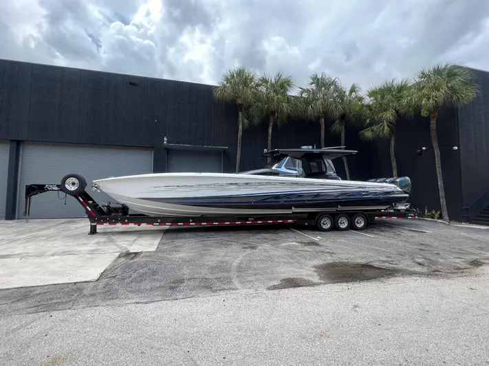  Yacht Photos Pics 2019 Nor-Tech 450 Sport boat on a trailer, parked outside a warehouse with palm trees.