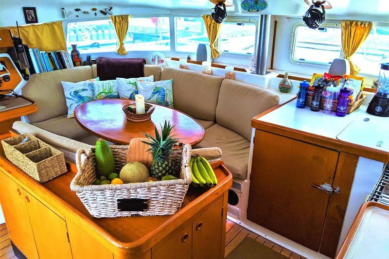 Guiding Light Yacht Photos Pics Cozy interior of 1997 Lagoon 410 catamaran with fruit basket and comfortable seating.