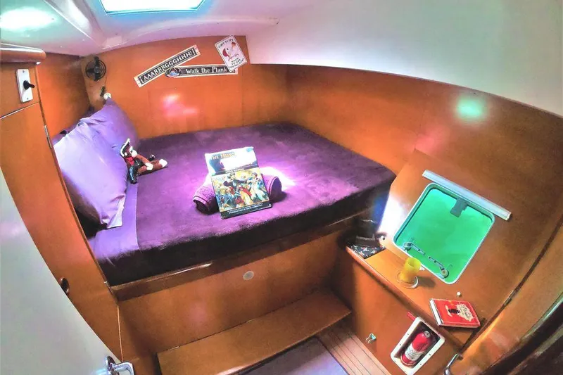 Guiding Light Yacht Photos Pics Cozy cabin interior of 1997 Lagoon 410 catamaran with purple bedding and wooden accents.