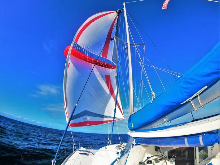 Guiding Light Yacht Photos Pics Lagoon 410 catamaran sailing with colorful spinnaker on open sea, 1997 model.
