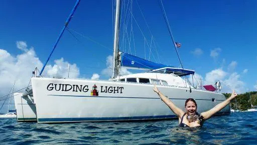 Guiding Light Yacht Photos Pics Woman swimming near 1997 Lagoon 410 catamaran "Guiding Light" in sunny waters.