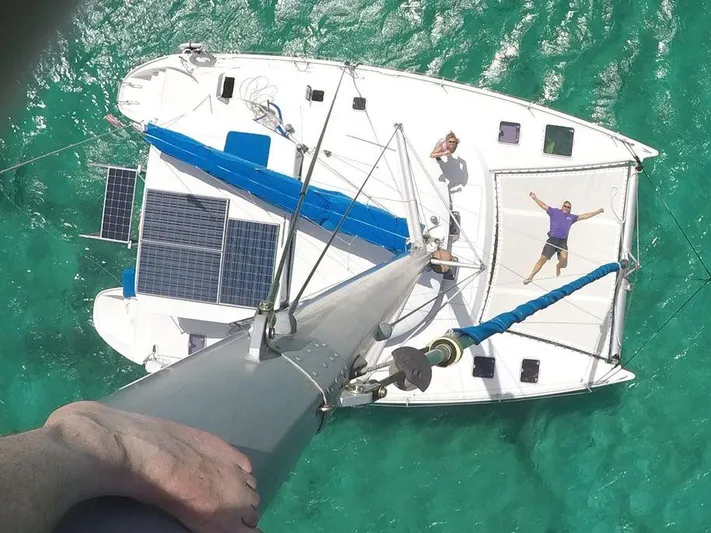 Guiding Light Yacht Photos Pics Aerial view of 1997 Lagoon 410 catamaran with solar panels and people relaxing on deck.