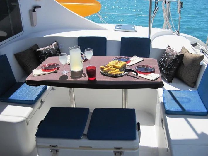 Guiding Light Yacht Photos Pics Cozy dining area on 1997 Lagoon 410 catamaran with food and drinks, ocean view.