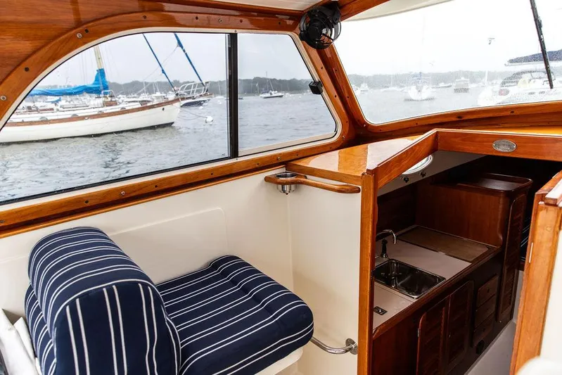 Calm Yacht Photos Pics Interior of a 1999 Hinckley Picnic Boat Classic with striped seating and wooden cabinetry.