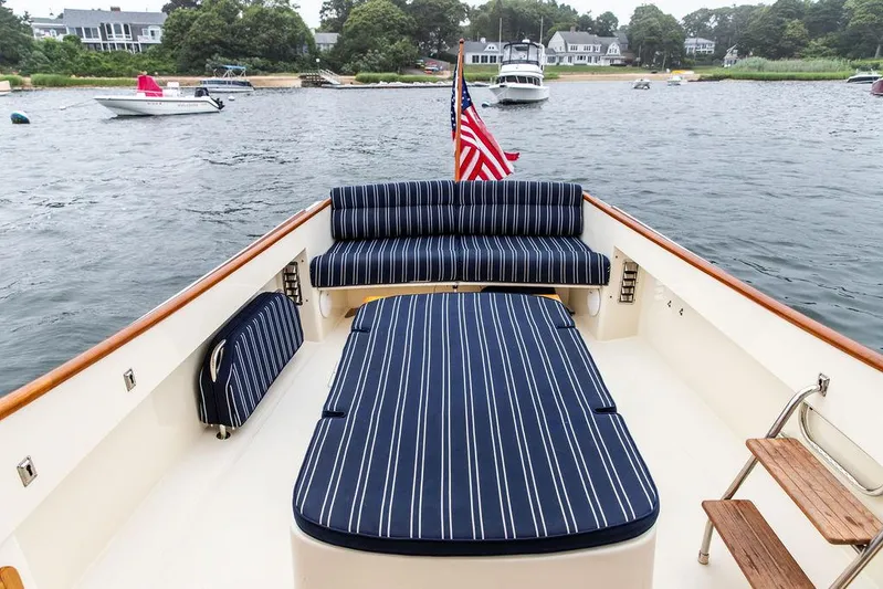 Calm Yacht Photos Pics 1999 Hinckley Picnic Boat Classic with striped seating, American flag, and scenic waterfront view.