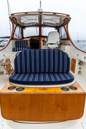 Calm Yacht Photos Pics 1999 Hinckley Picnic Boat Classic with striped seating and wooden accents, docked at a marina.