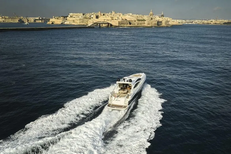  Yacht Photos Pics 2010 Sunseeker Predator 64 yacht cruising near a historic coastal city.
