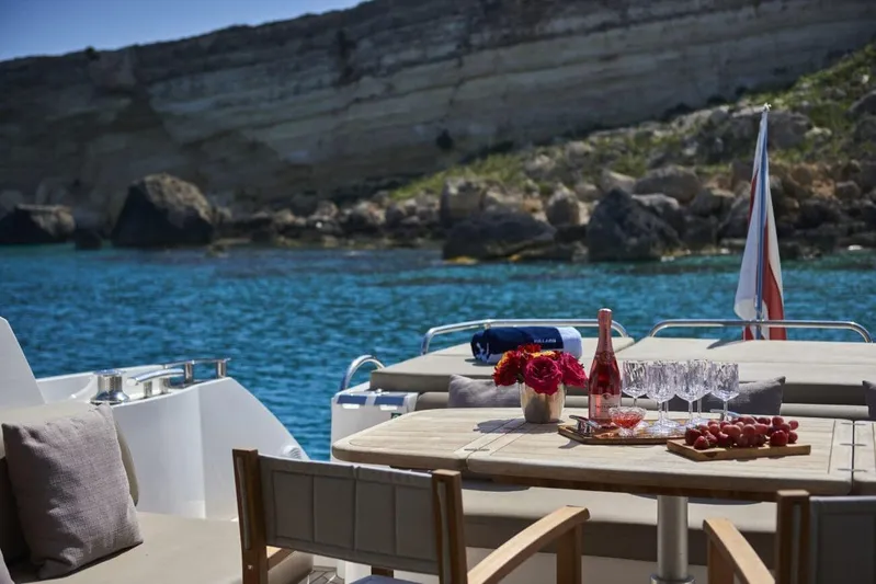  Yacht Photos Pics Luxurious Sunseeker Predator 64 yacht with elegant outdoor dining setup, scenic coastal backdrop.