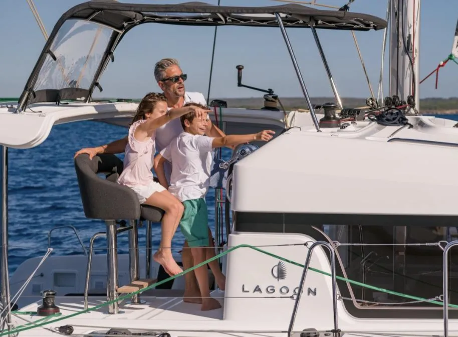 Family enjoying sailing on a 2020 Lagoon 40 catamaran in sunny weather.