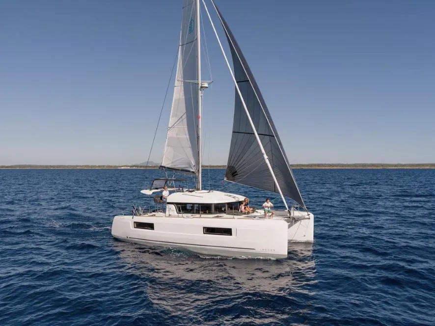 2020 Lagoon 40 catamaran sailing on open sea under clear blue sky.