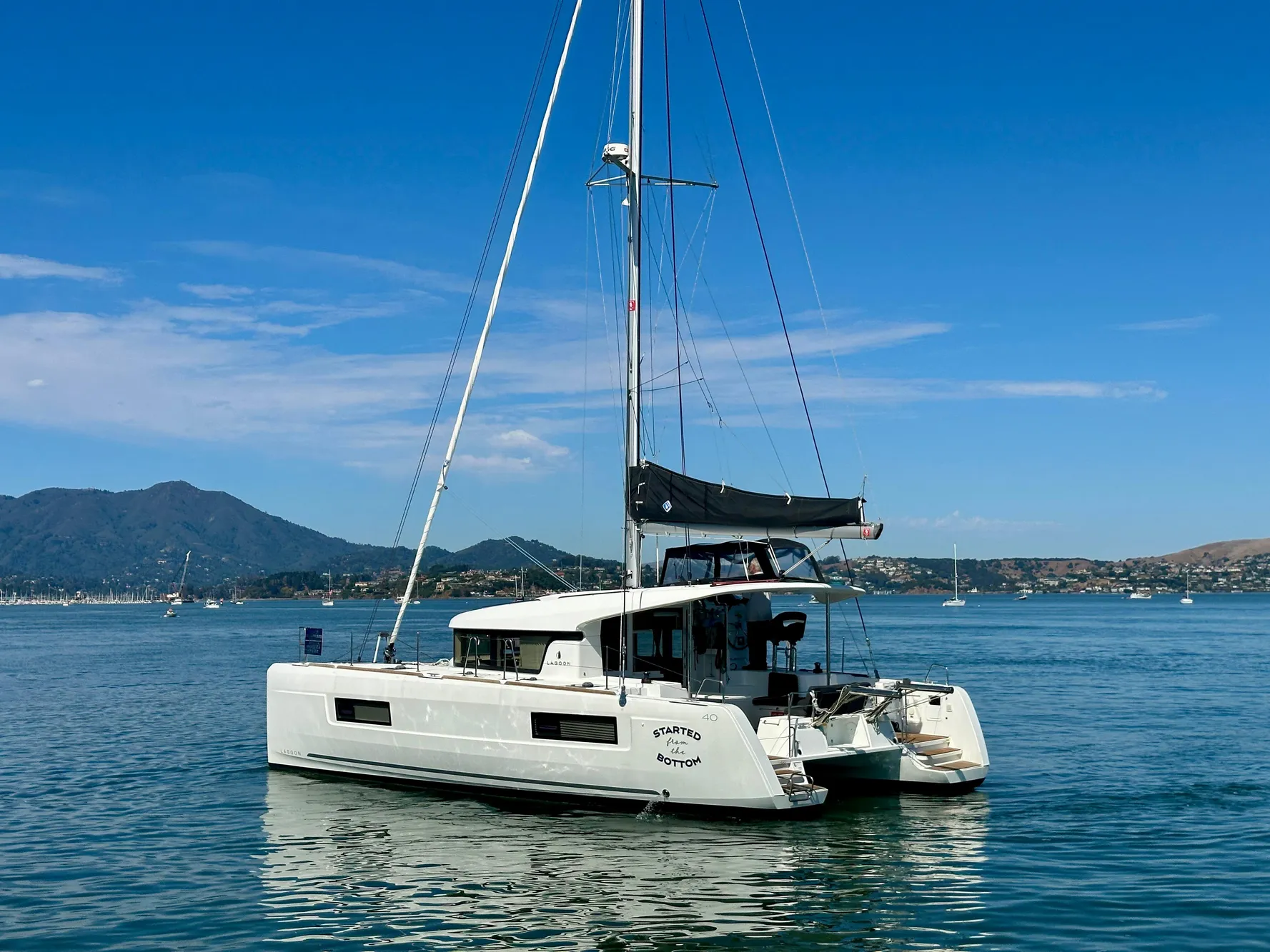 2020 Lagoon 40 catamaran sailing on calm waters with scenic mountain backdrop.