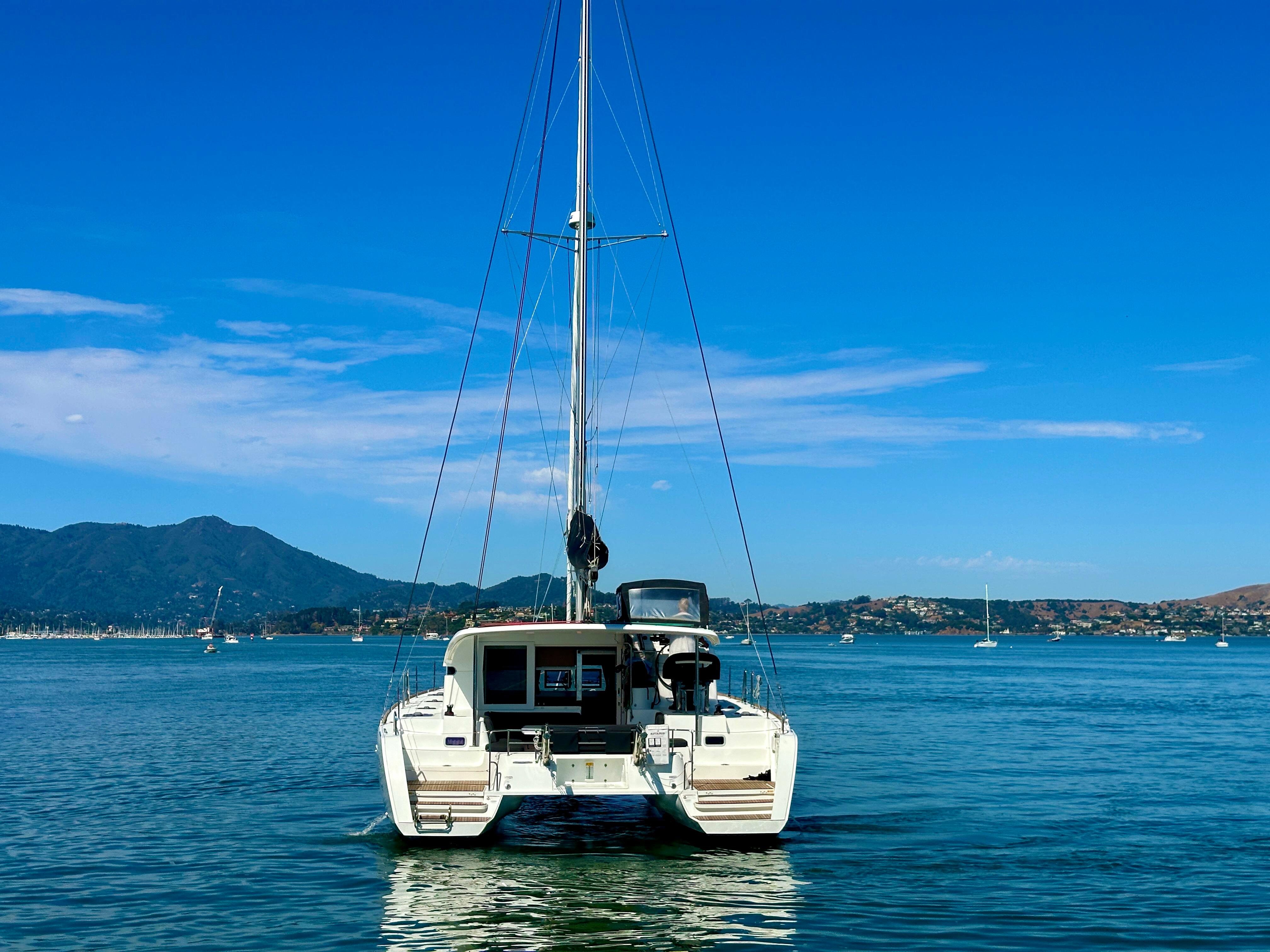2020 Lagoon 40 catamaran on calm water with scenic mountain backdrop.