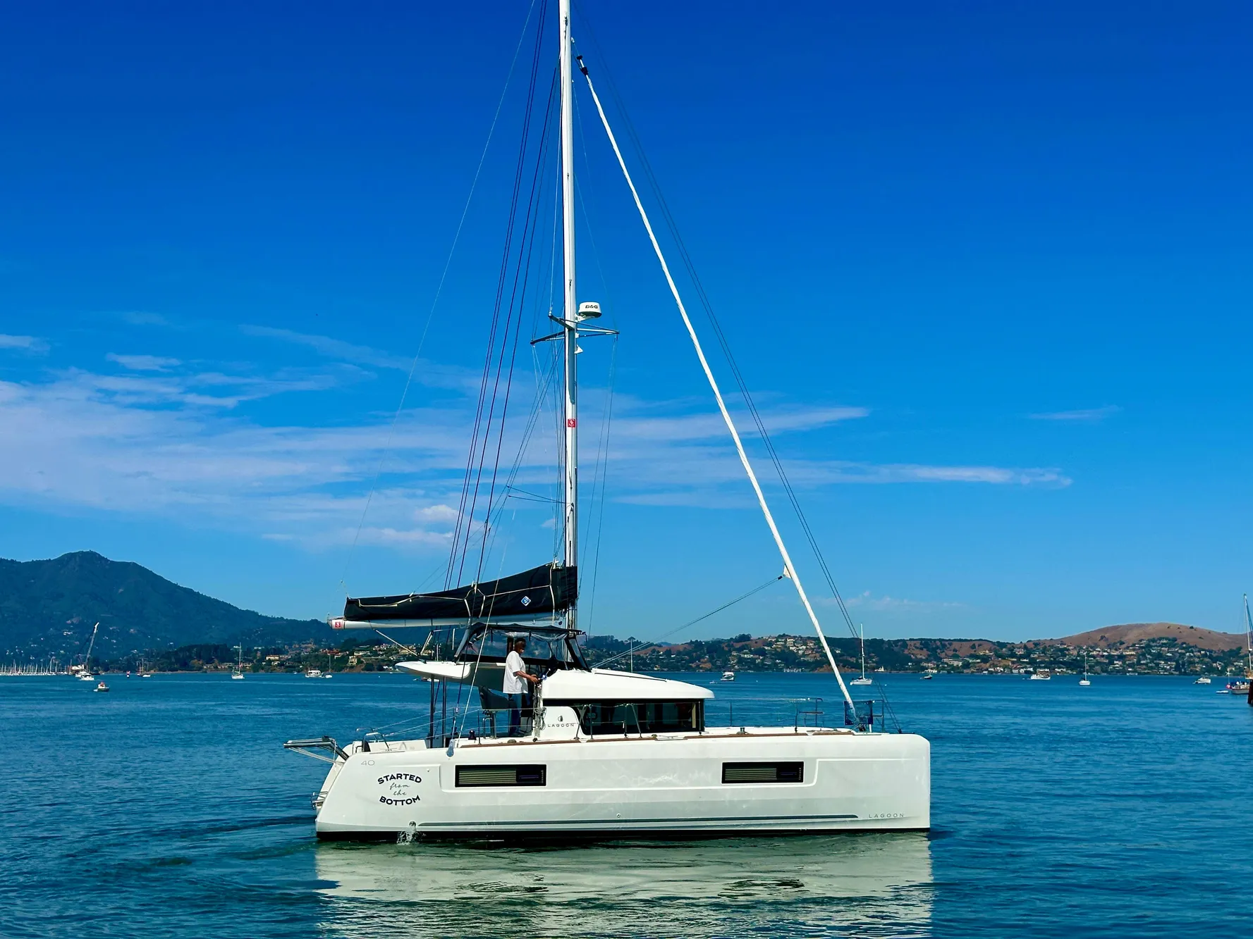 2020 Lagoon 40 catamaran sailing on calm waters with scenic mountain backdrop.