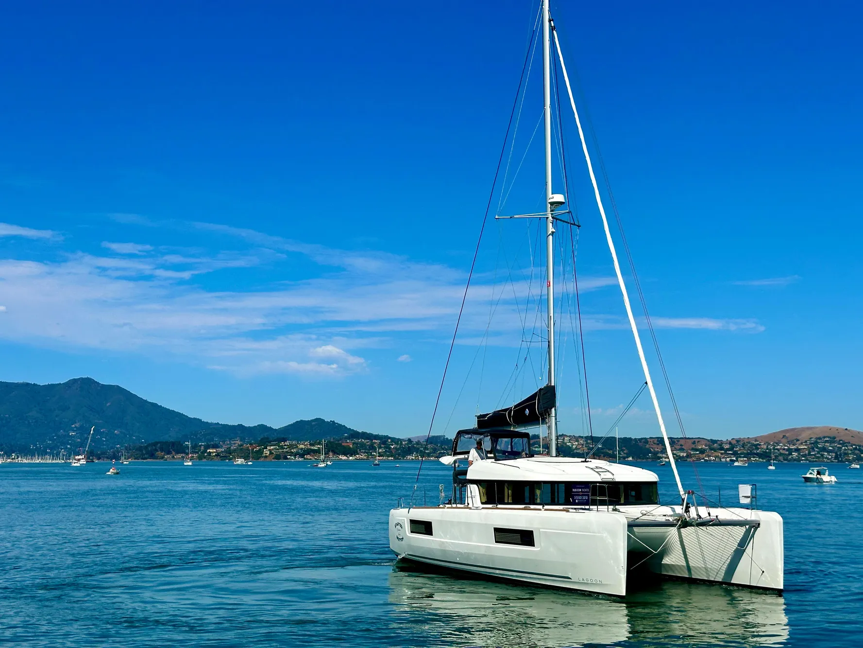 2020 Lagoon 40 catamaran sailing on calm waters with scenic mountain backdrop.