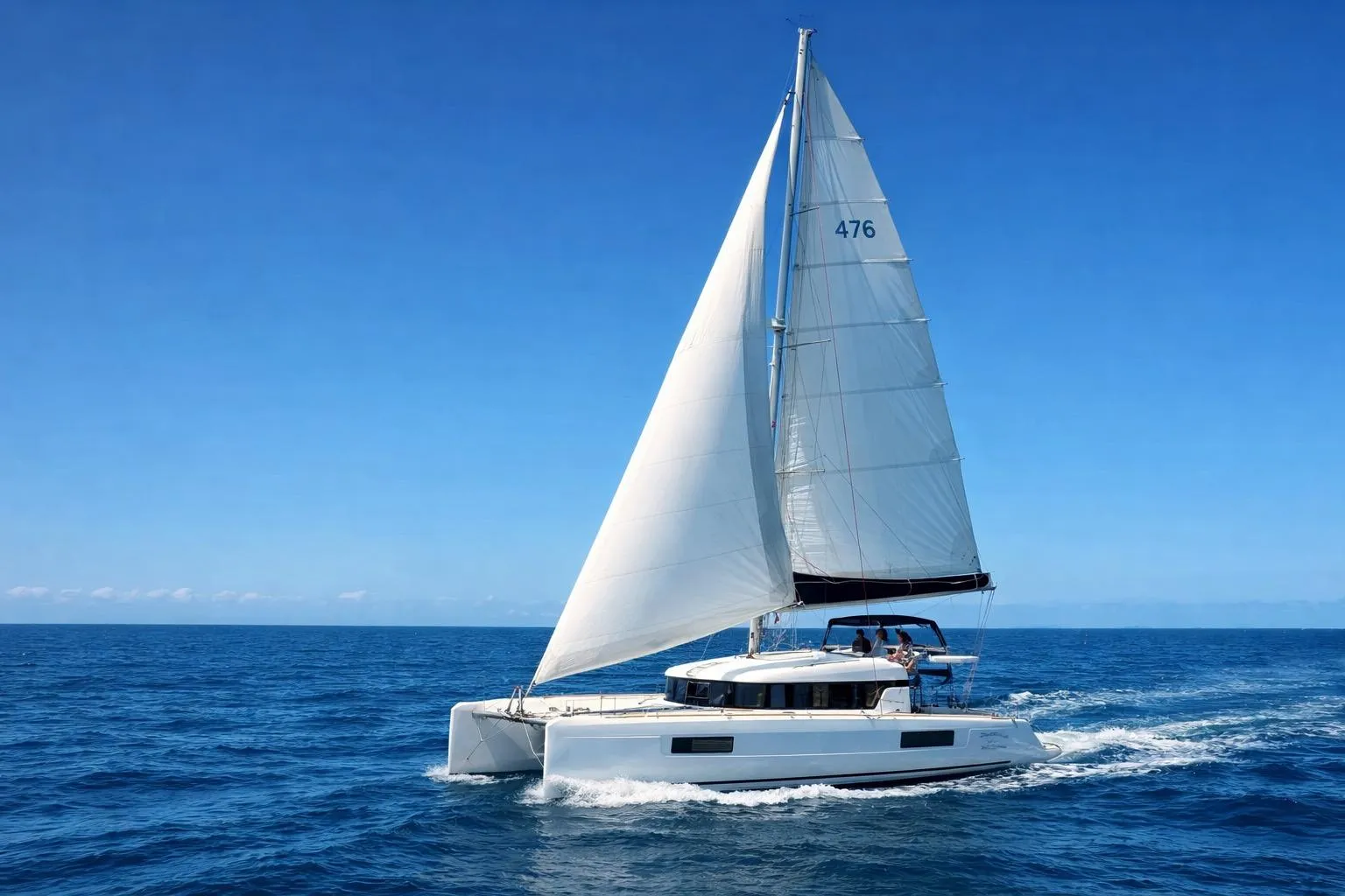 2020 Lagoon 40 catamaran sailing on open ocean under clear blue sky.
