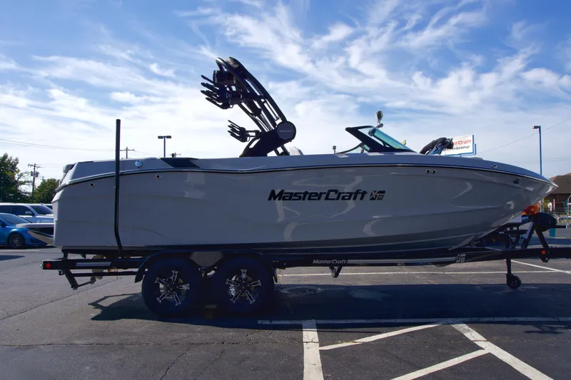  Yacht Photos Pics 2025 MasterCraft XT23 boat on trailer in parking lot, side view.