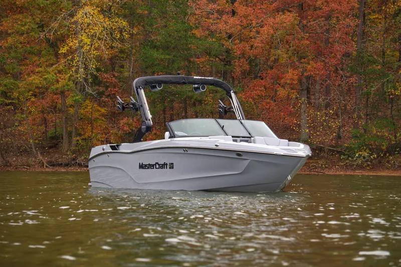  Yacht Photos Pics 2025 MasterCraft XT23 boat on a lake with autumn foliage background.