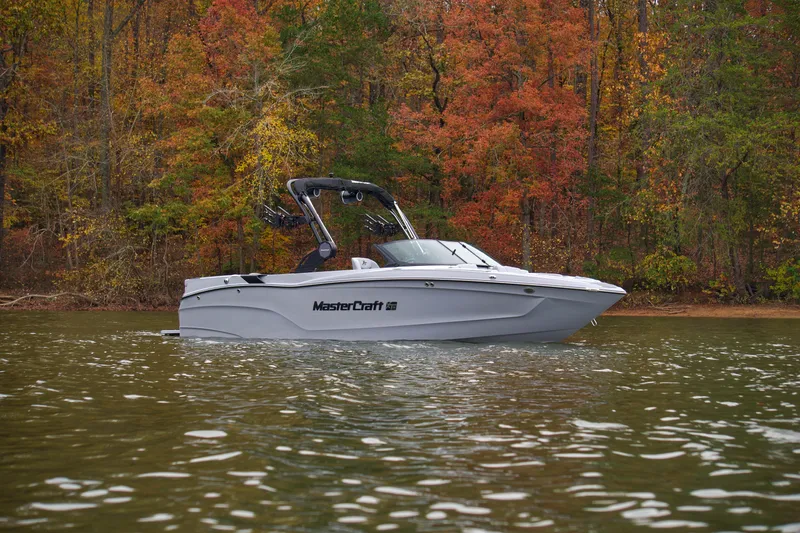  Yacht Photos Pics 2025 MasterCraft XT23 boat on a lake with autumn foliage background.