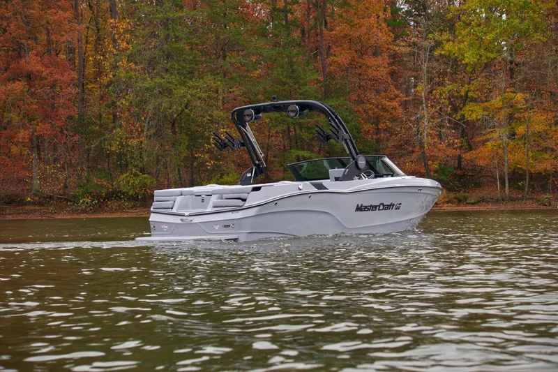  Yacht Photos Pics 2025 MasterCraft XT23 boat cruising on a lake with autumn foliage backdrop.