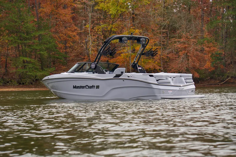  Yacht Photos Pics 2025 MasterCraft XT23 boat on a lake with autumn foliage background.