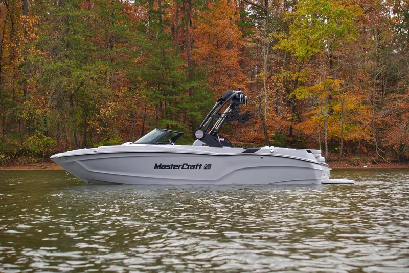  Yacht Photos Pics 2025 MasterCraft XT23 boat on a lake with autumn trees in the background.