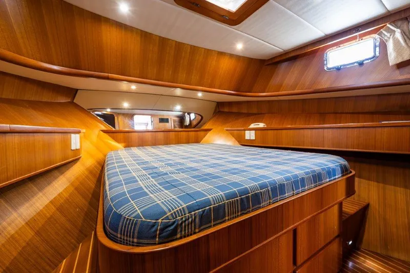  Yacht Photos Pics Cozy cabin interior of 2000 Symbol 42 Classic Trawler with wood paneling and plaid bedding.