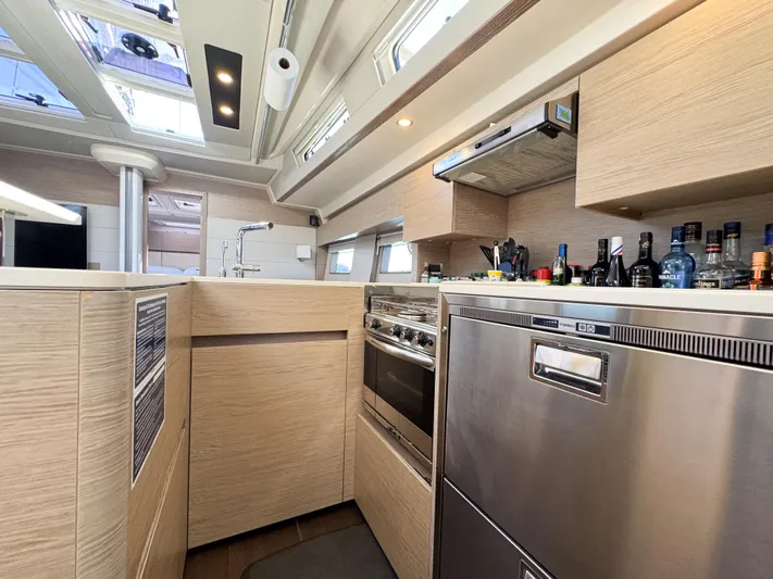  Yacht Photos Pics Modern kitchen interior of 2019 Hanse 588 yacht with appliances and wooden cabinetry.
