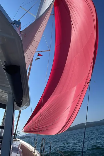  Yacht Photos Pics Sailing yacht Hanse 588 (2019) with vibrant red sail on open water.
