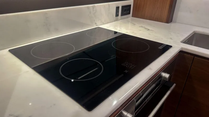 F55163 Yacht Photos Pics Modern kitchen with sleek black induction cooktop on marble countertop, Princess F55, 2023 model.