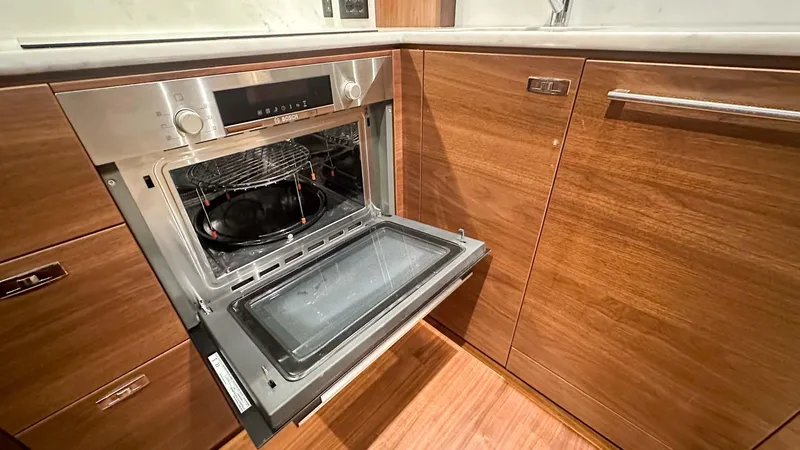 F55163 Yacht Photos Pics Modern kitchen with open oven in 2023 Princess F55 yacht, featuring sleek wooden cabinetry.