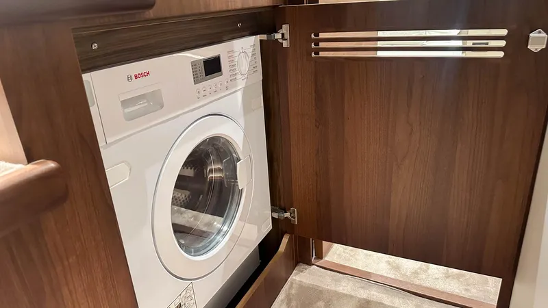 F55163 Yacht Photos Pics Built-in Bosch washing machine in a 2023 Princess F55 yacht's wooden cabinet.