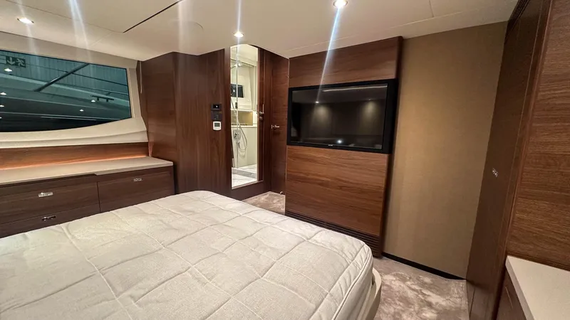 F55163 Yacht Photos Pics Luxurious 2023 Princess F55 yacht bedroom with modern wood finishes and large TV.