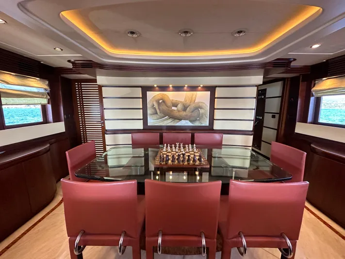 Lady Moh Yacht Photos Pics Luxurious Bugari 95 yacht dining area with glass table, red chairs, and chess set, 2002 model.