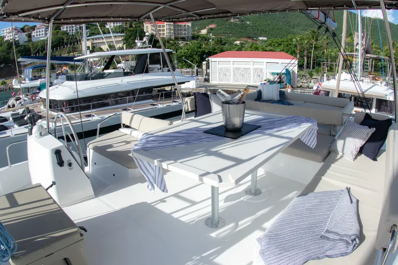  Yacht Photos Pics Spacious deck of 2021 Bali 4.8 catamaran with seating and table, docked at marina.