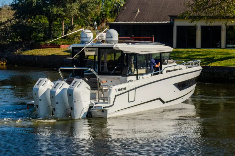  Yacht Photos Pics 2025 Wellcraft 355 boat cruising on a calm river with triple outboard engines.